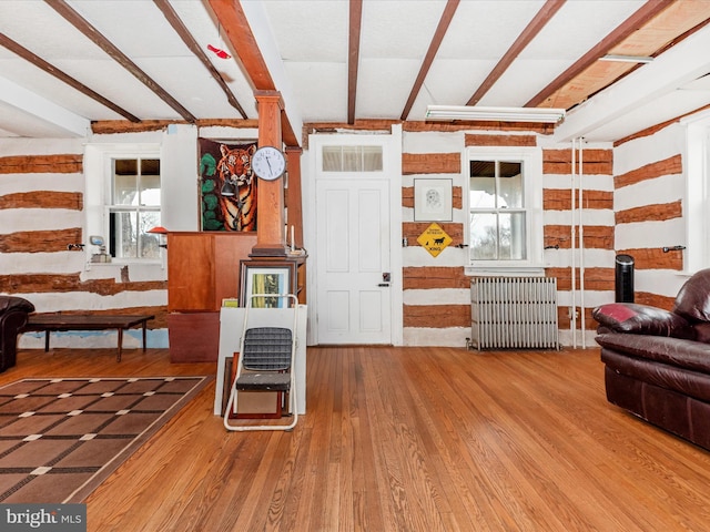 living room with beamed ceiling, radiator, and wood finished floors