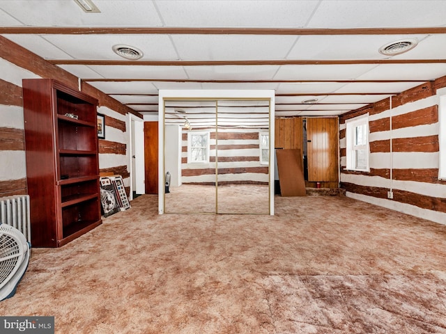 basement featuring visible vents, a paneled ceiling, and carpet