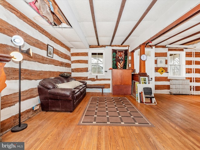 living area with beam ceiling, radiator heating unit, and wood finished floors