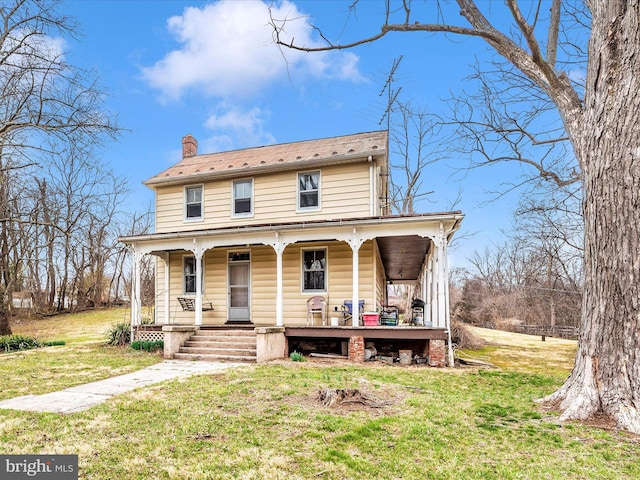 view of front facade with a porch, a front yard, and a chimney