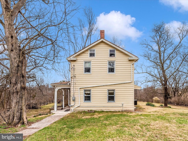 rear view of house featuring a lawn and a chimney