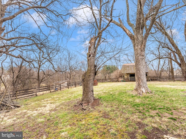 view of yard with a rural view, a barn, an outdoor structure, and fence