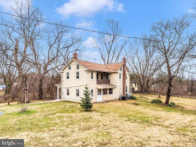 view of property exterior featuring a balcony, cooling unit, a lawn, and a chimney