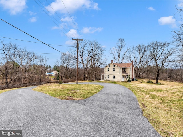 view of front of home featuring aphalt driveway, a chimney, and a front yard