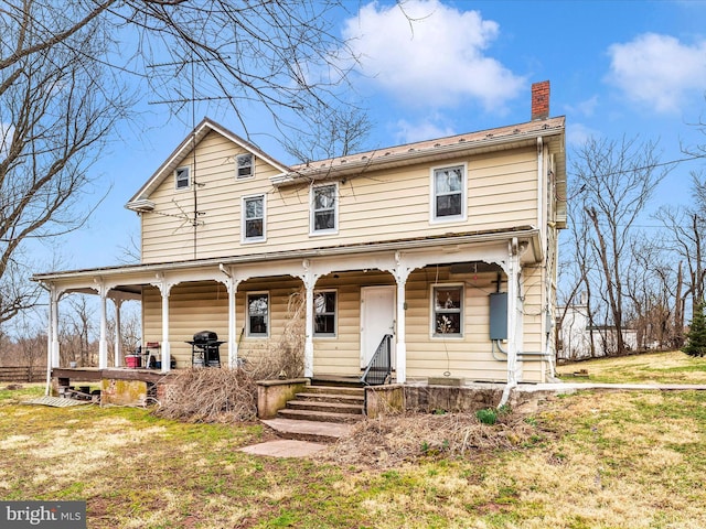 view of front of house featuring a porch, a chimney, and a front yard