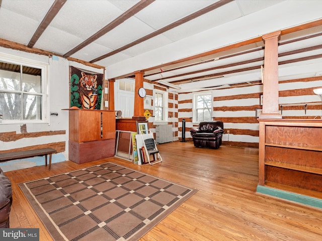 interior space featuring beam ceiling, wood finished floors, and ornate columns