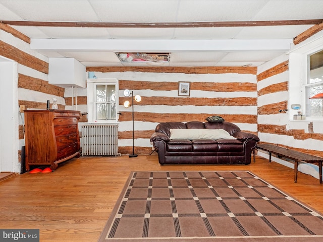 living room featuring beam ceiling, radiator, and wood finished floors