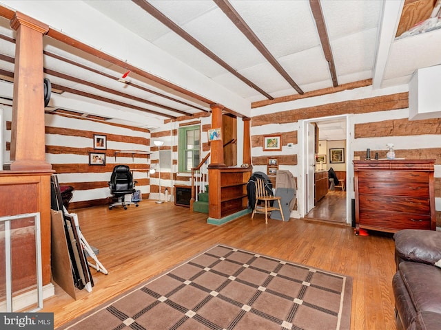 living area featuring beam ceiling and wood finished floors