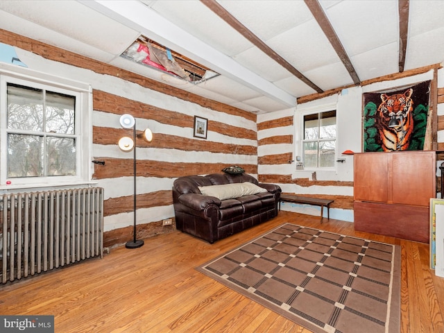 sitting room with beam ceiling, wood finished floors, and radiator heating unit