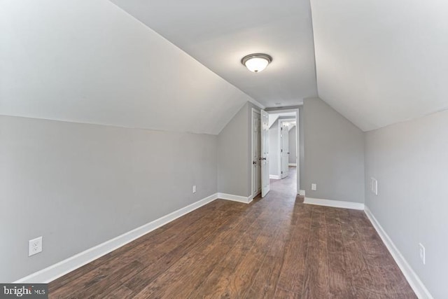 additional living space featuring baseboards, vaulted ceiling, and dark wood-style flooring