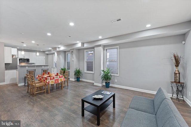 living area featuring dark wood-style floors, baseboards, visible vents, and recessed lighting