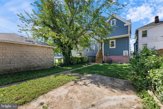 rear view of property with cooling unit, a yard, and entry steps