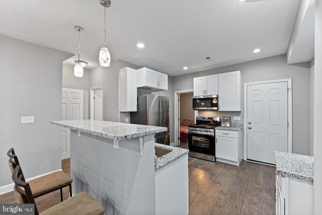 kitchen with stainless steel appliances, dark wood-type flooring, white cabinetry, and a kitchen breakfast bar