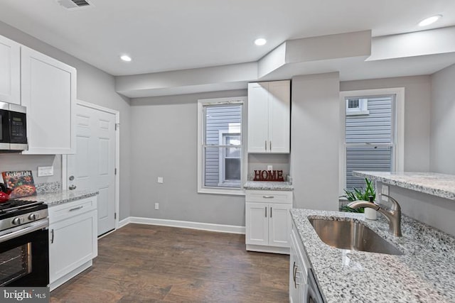 kitchen with stainless steel appliances, dark wood-type flooring, a sink, baseboards, and white cabinets