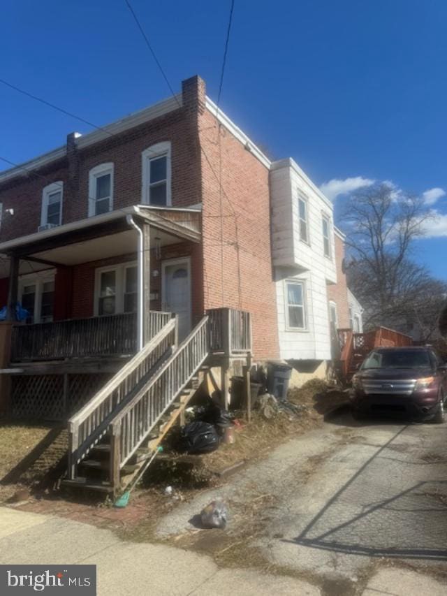 view of side of property featuring covered porch and brick siding