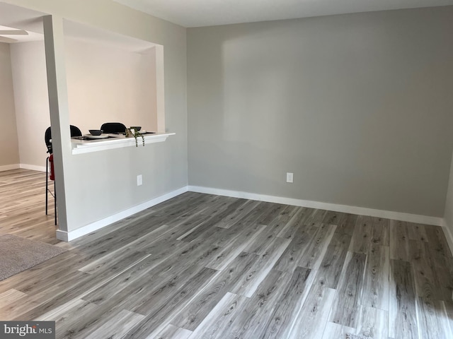 spare room with baseboards and wood finished floors