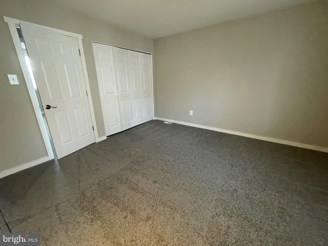 unfurnished bedroom featuring a closet, baseboards, and dark colored carpet