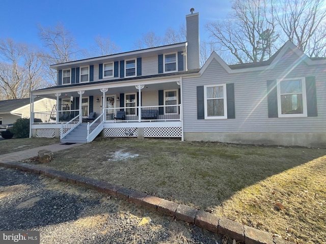 view of front of property featuring a chimney, a porch, and a front yard