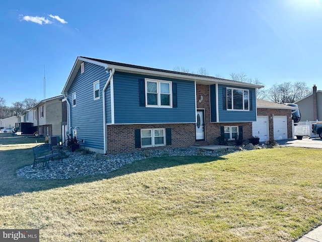 bi-level home with a garage, brick siding, driveway, and a front yard