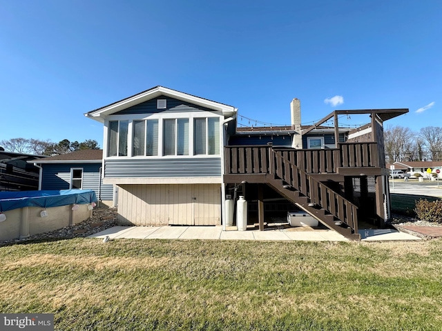 back of house featuring stairs, a deck, and a lawn