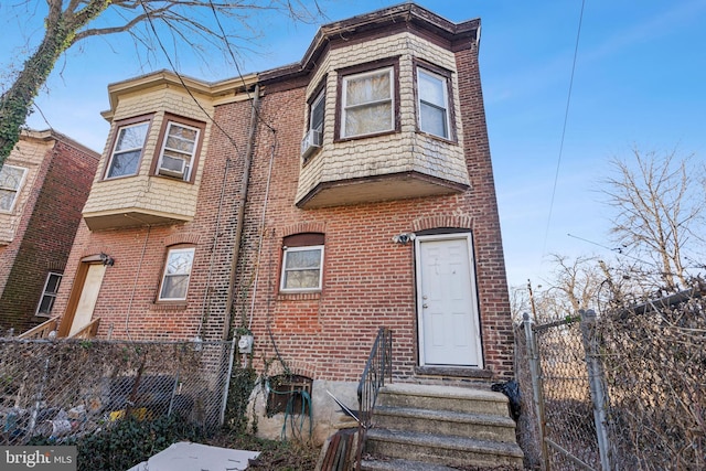 view of property featuring brick siding and fence