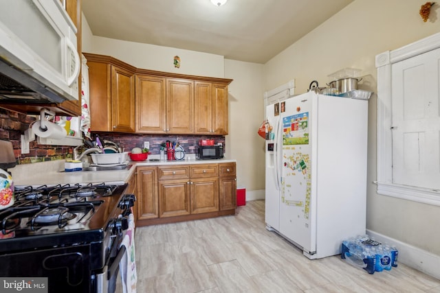 kitchen with white appliances, baseboards, decorative backsplash, light countertops, and brown cabinets