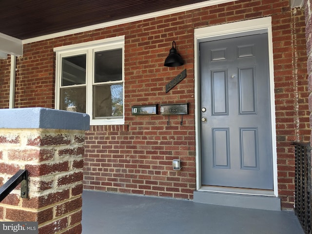 view of exterior entry with covered porch and brick siding