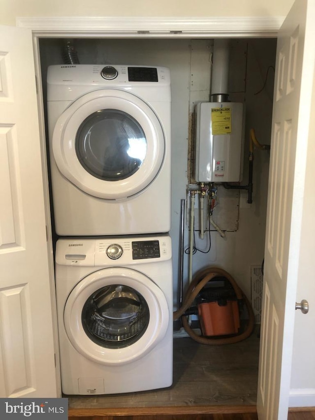 laundry room featuring water heater, laundry area, and stacked washer / drying machine