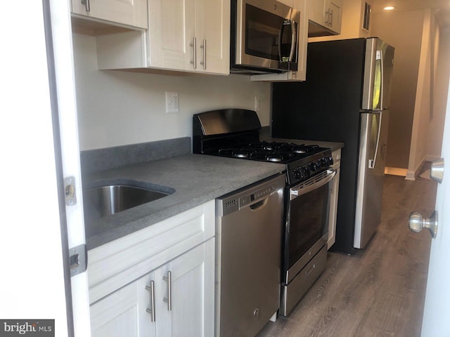 kitchen featuring a sink, appliances with stainless steel finishes, dark wood finished floors, and white cabinets