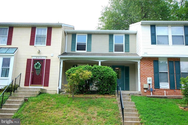 townhome / multi-family property with entry steps, a front lawn, and brick siding