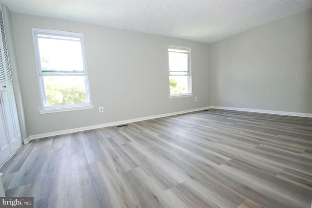 spare room featuring visible vents, light wood-type flooring, and baseboards