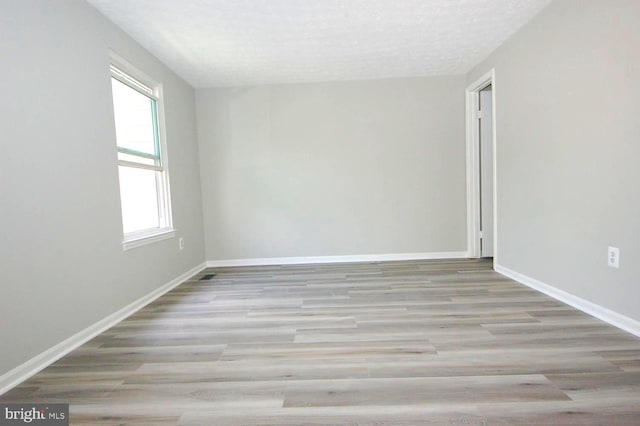 spare room with baseboards, a textured ceiling, and wood finished floors