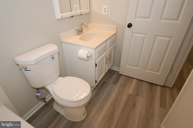 bathroom featuring baseboards, toilet, wood finished floors, and vanity