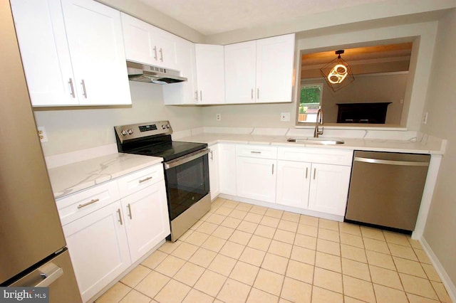 kitchen with under cabinet range hood, light stone counters, a sink, white cabinetry, and stainless steel appliances