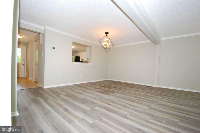 unfurnished living room featuring a textured ceiling, crown molding, baseboards, and wood finished floors