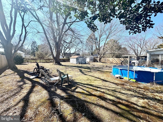 view of yard featuring a storage unit, an outdoor structure, fence, and a fenced in pool