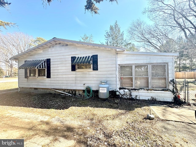 view of side of home with crawl space and fence