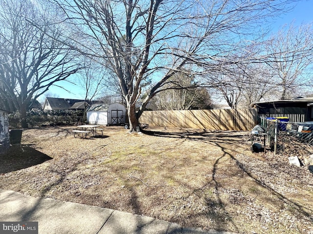 view of yard with a storage shed, an outbuilding, and fence