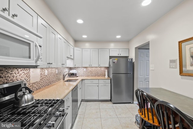 kitchen featuring light tile patterned floors, recessed lighting, a sink, decorative backsplash, and stainless steel appliances