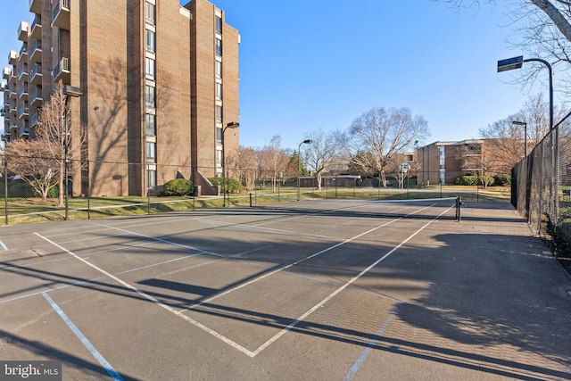 view of tennis court with community basketball court and fence