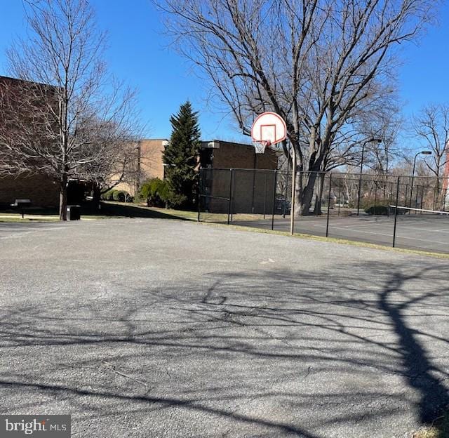 exterior space featuring a tennis court, community basketball court, and fence