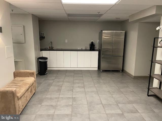 kitchen featuring a paneled ceiling, dark countertops, and freestanding refrigerator