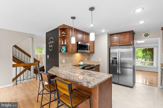 kitchen with open shelves, light stone counters, backsplash, stainless steel appliances, and a peninsula