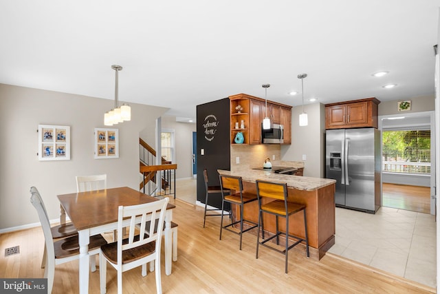 dining room with stairway, light wood-style floors, and baseboards