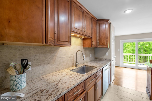 kitchen featuring light stone counters, light tile patterned floors, a sink, decorative backsplash, and dishwasher