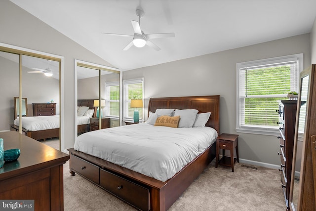 bedroom featuring two closets, multiple windows, light colored carpet, and vaulted ceiling