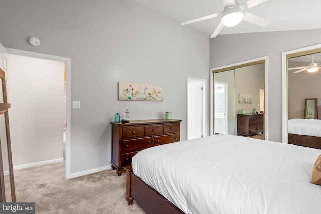 bedroom featuring baseboards, lofted ceiling, ceiling fan, multiple closets, and light carpet