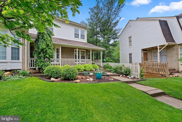 view of front of house featuring brick siding, covered porch, a front lawn, and a shingled roof