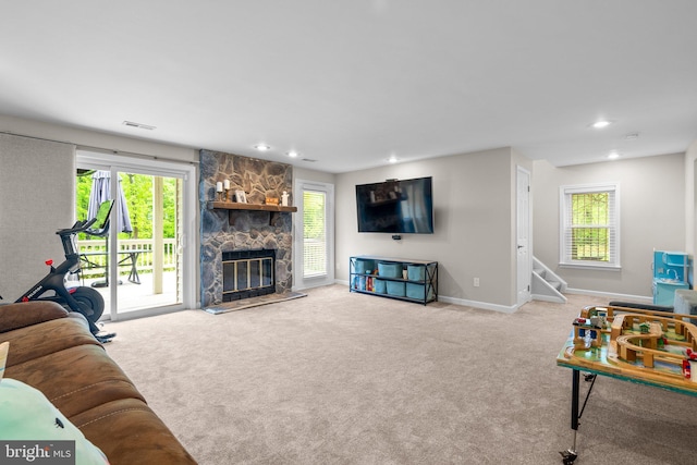 living area featuring visible vents, baseboards, carpet, a stone fireplace, and recessed lighting