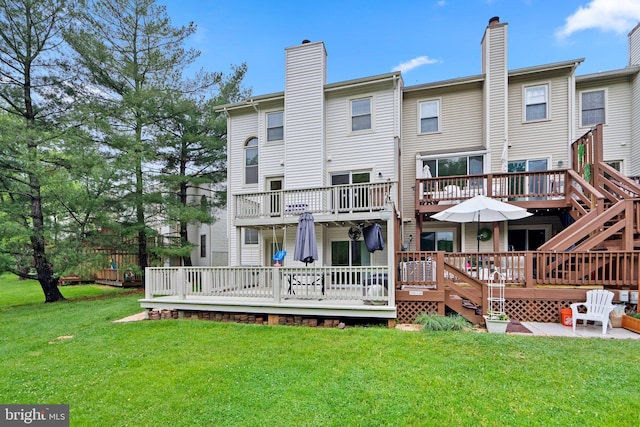 back of house with a wooden deck, a lawn, and a chimney